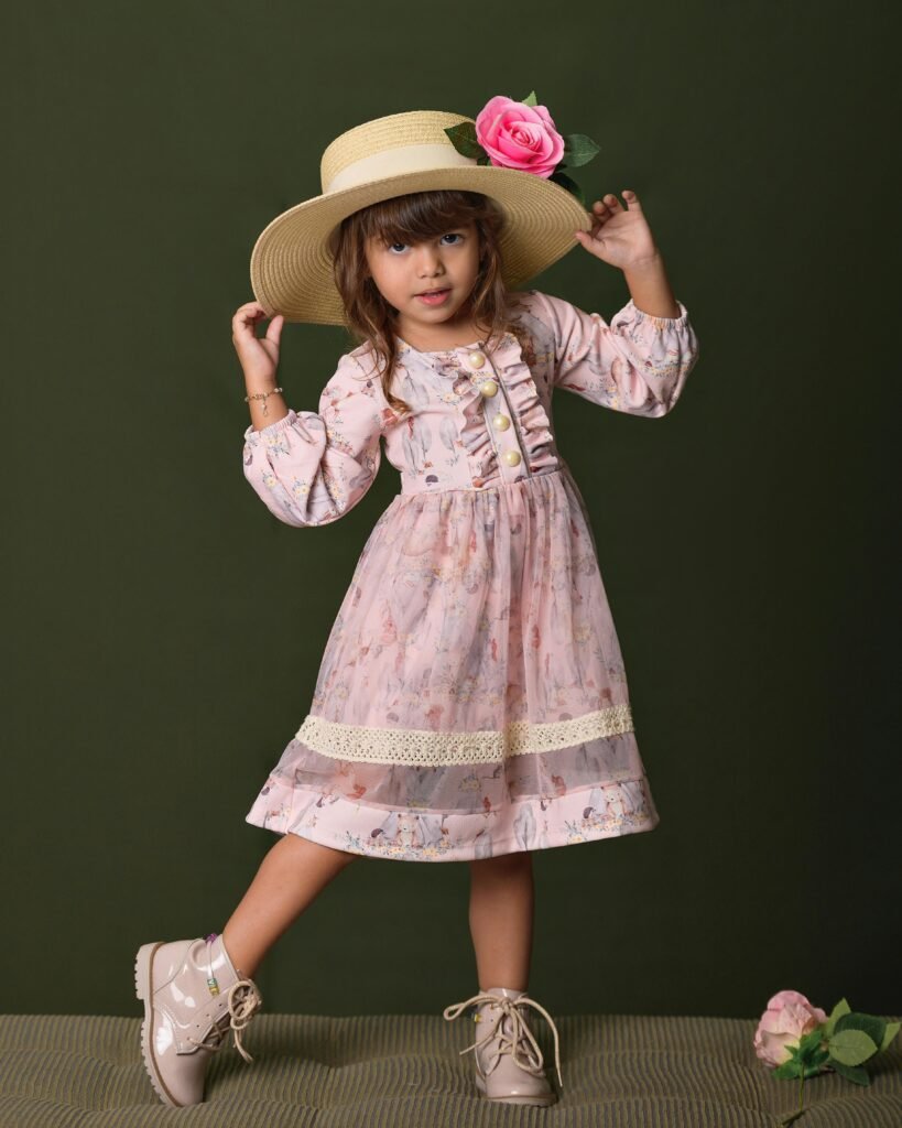 pexels-photo-16802205-16802205 Adorable girl in a pink floral dress and straw hat posing against a green background.