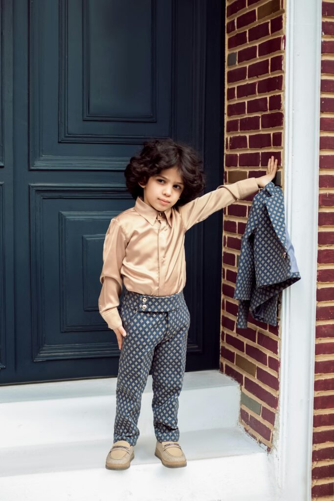 pexels-photo-20215089-20215089 A young child dressed impeccably in a fashionable outfit poses confidently by a doorway in an urban setting.